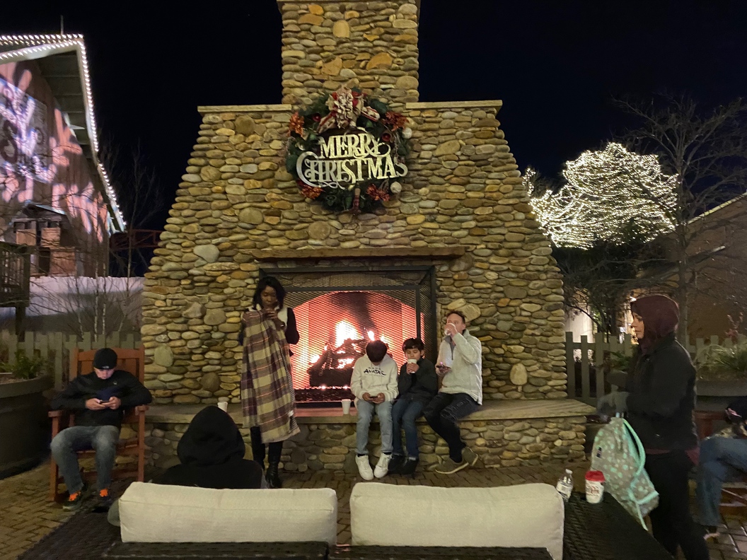 This is a gas-burning fireplace near the Mountain Gliders ride. People can sit on the outdoor furniture to enjoy the fireplace.