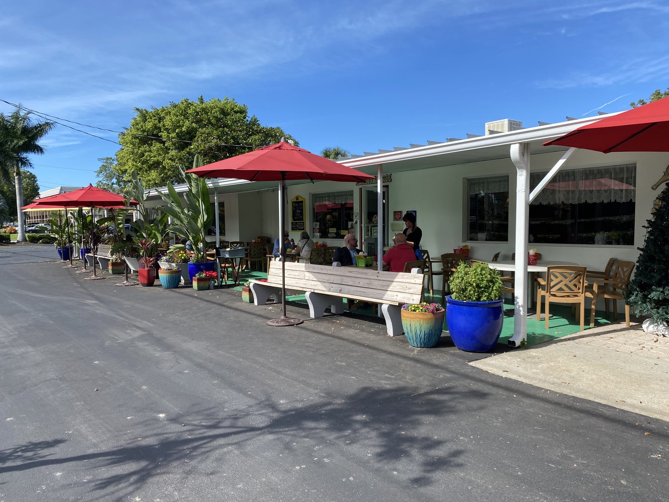 There are a variety of potted plants and benches in front of
      Dolly's.