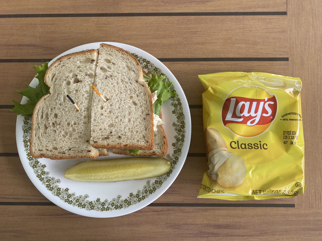 This chicken salad sandwich on wheat bread comes with chips
      and a pickle.